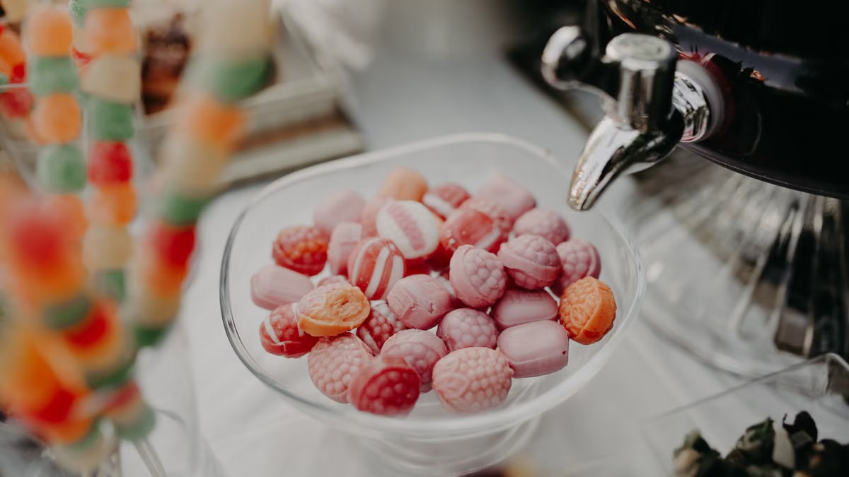 Vibrant close-up of assorted pink and orange candies in a glass dish, perfect for sweet-themed designs.